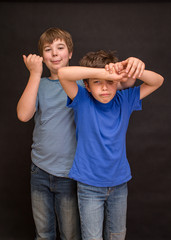 Brothers having fun whilst posing. Boys portrait, young little cute and adorable kids, little obstreperous scamps. Poses, face expressions, ease,  black background. - obrazy, fototapety, plakaty