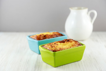 Breakfast casserole in cute baking dishes on a white weathered wood background mock up