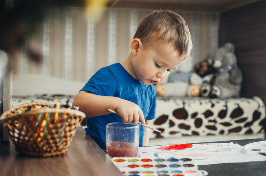 the baby in the nursery, with enthusiasm draws paints