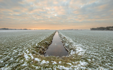 Frozen grassland with straight river canal