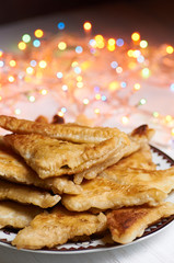Small triangular patties with filling. New Year's, Christmas multicolored lights in the background. Christmas treat for Santa Claus. Fried, baked pies.