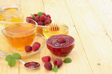 healthy background. raspberry with raspberry jam, honey and tea on light wooden background