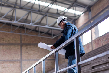 Senior construction manager controlling building site with plan.