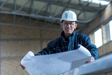 Senior construction manager controlling building site with plan.