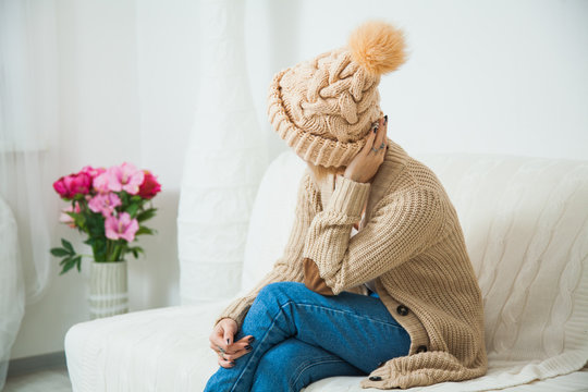 Young woman in warm beige hand knitted hat at home.
