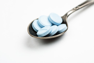 Medications in a metal spoon on a white background