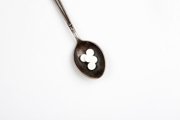 Medications in a metal spoon on a white background