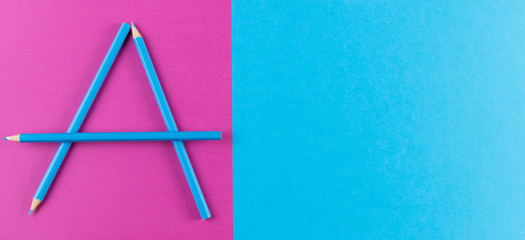 Blue pencils arranged as letter A on purple and blue contrast background.