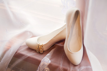 Snow-white wedding shoes with an ornament on a window sill on a