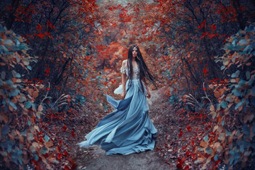 Mysterious fantasy woman elf sorceress in blue dress. Long brunette hair fly fluttering in wind...