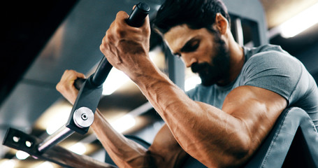 Young handsome man doing exercises in gym