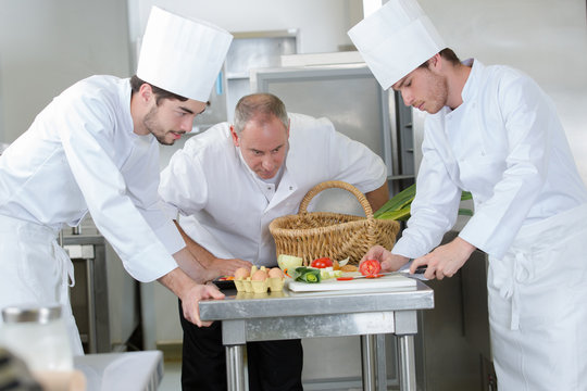 professional chef and his apprentices preparing a dish at restaurant