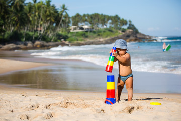 Kid plays with toys at the seashore in summertime