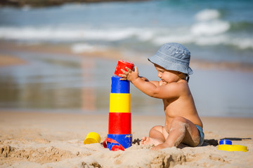 Kid plays with toys at the seashore in summertime
