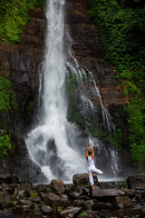Woman practices yoga at Gitgit waterfall on Bali in indonesia