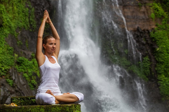 Woman practices yoga at Gitgit waterfall on Bali in indonesia