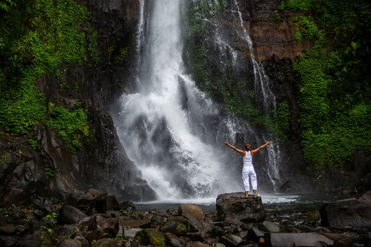Woman practices yoga at Gitgit waterfall on Bali in indonesia