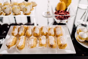 Wedding reception dessert table with delicious decorated white cupcakes with frosting closeup