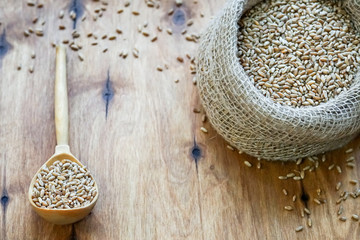 A bag of grain is on the table. There is a wooden spoon nearby
