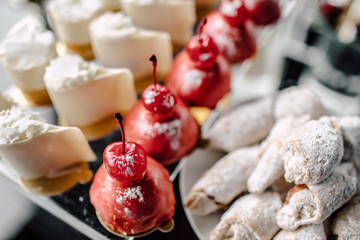 Wedding reception dessert table with delicious decorated white cupcakes with frosting closeup