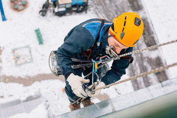 Professional industrial climber in helmet and uniform works at height. Risky extreme job.