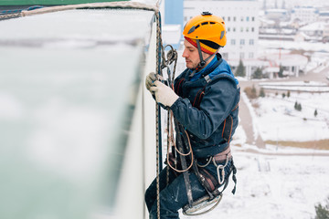 Professional industrial climber in helmet and uniform works at height. Risky extreme job.