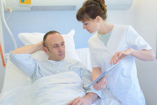 nurse talking to male patientin hospital bed