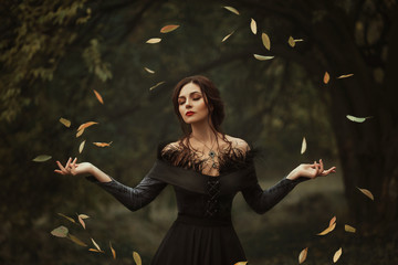 Incredible, amazing, seductive girl, in a black dress , magic rotates the leaves. background is...