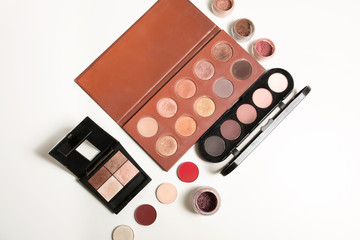 Kit of makeup palettes in nude color with loose eyeshadows over a white background