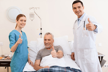 Obraz premium The old man lies on a cot in the medical ward, and next to him is a nurse and a doctor.