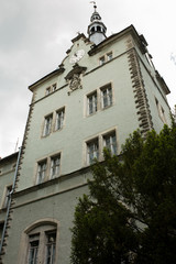 Facade of old castle with stucco, clock, and the coat of arms