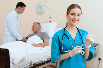 The old man lies on a cot in the medical ward, and next to him there is a doctor and a nurse.