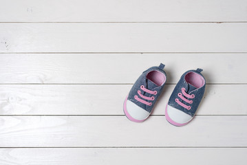 Baby shoes on white wooden table.