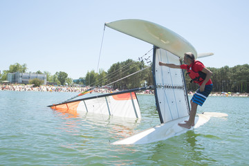 salior trying to right his catamaran after capsize