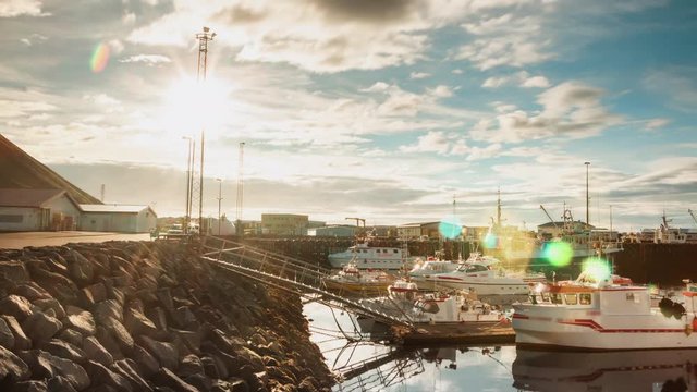 Northern harbor port in the fjord with fishing and whale watching boats in the evening sun light in Iceland with mountain timelapse
