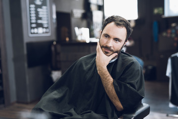 A man sits in a barber's chair in a man's barbershop, where he came to cut his hair.