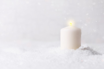 Burning candle in snow