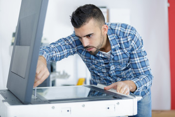 young male technician repairing digital photocopier machine