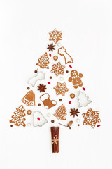 Christmas tree made of gingerbread cookies, stars anise, baking molds and pearls on white background. Christmas and New Year symbol. Flat lay.