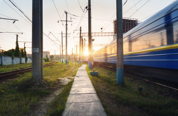 High speed passenger train in motion on railroad track at sunset. Railway station with blurred...