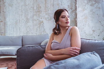Fototapeta premium Junge Frau in Kleid sitzt in bequemen Stuhl und trinkt Wein