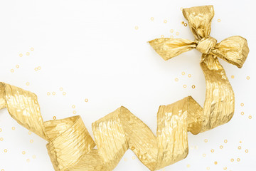 Decorative Golden Bow and wide helix ribbon with gold confetti on white. Festive background....