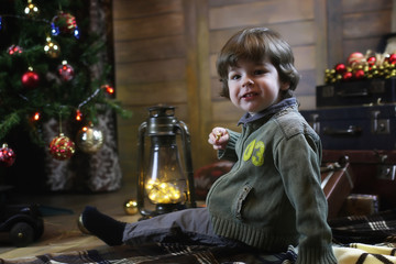 Child is sitting with Christmas decorations