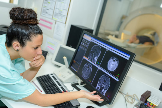 female assistant monitoring mri process in the control room