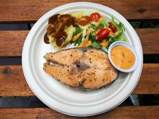 Salmon steak , mash potatoes and salad on wood table