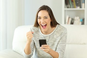 Excited woman holding phone looking at you