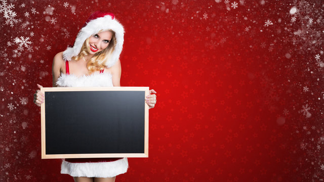 Weihnachtsfrau mit leerer Kreidetafel vor rotem Weihnachtshintergrund