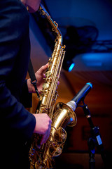 Obraz na płótnie Canvas Saxophone in the hands of a musician near the microphone