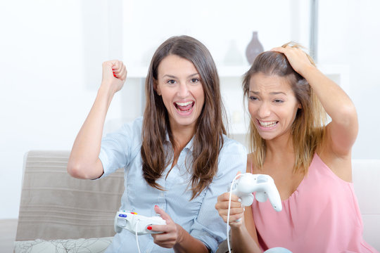happy excited girls lying in bedroom and playing video game