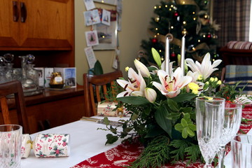 Beautiful floral centerpiece with candles on a festive dining table laid ready for Christmas Dinner in a traditional home